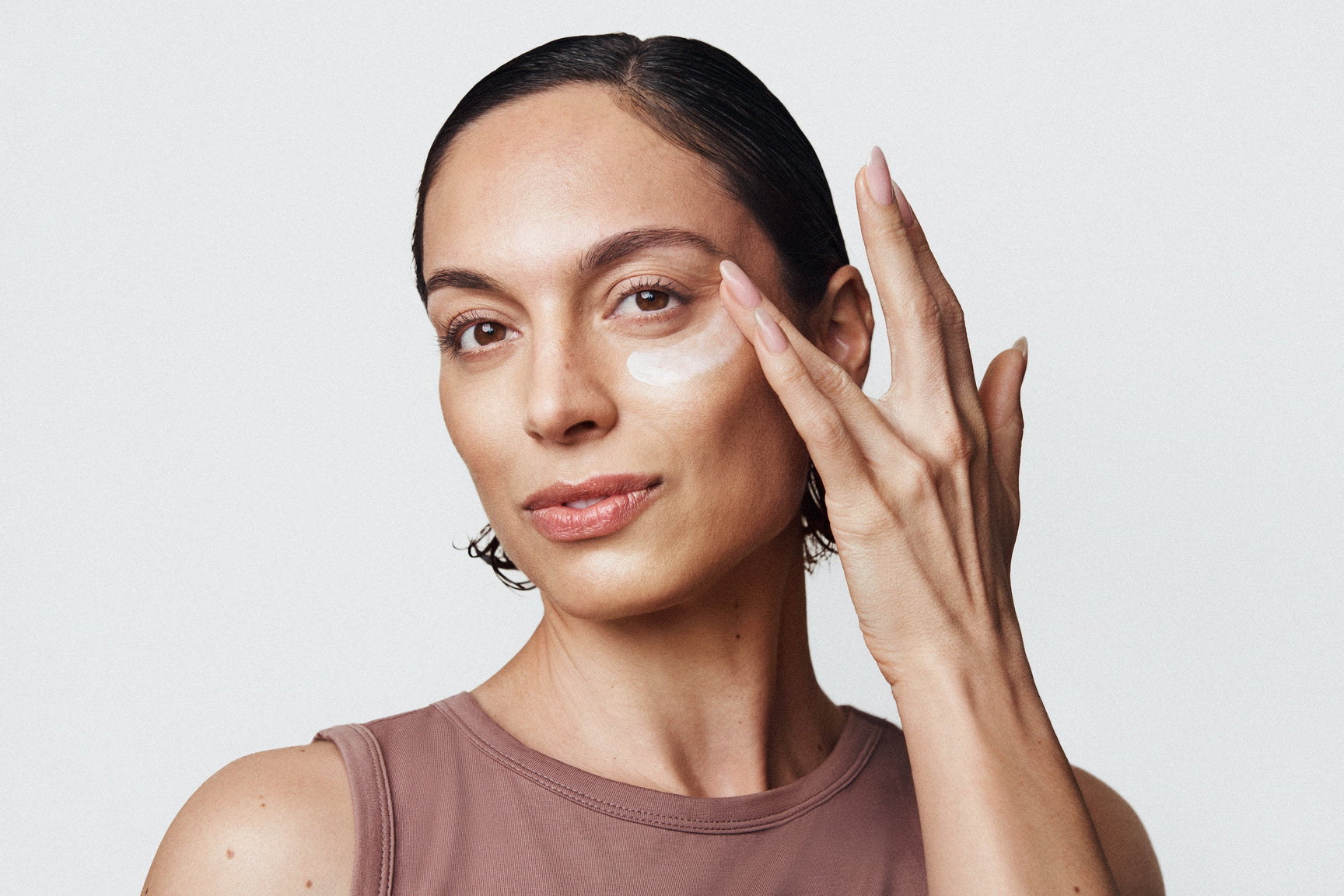 An image of a woman applying eye cream under her eyes