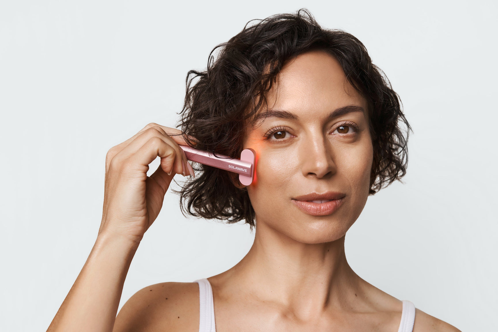 An image of a woman using red light therapy for face