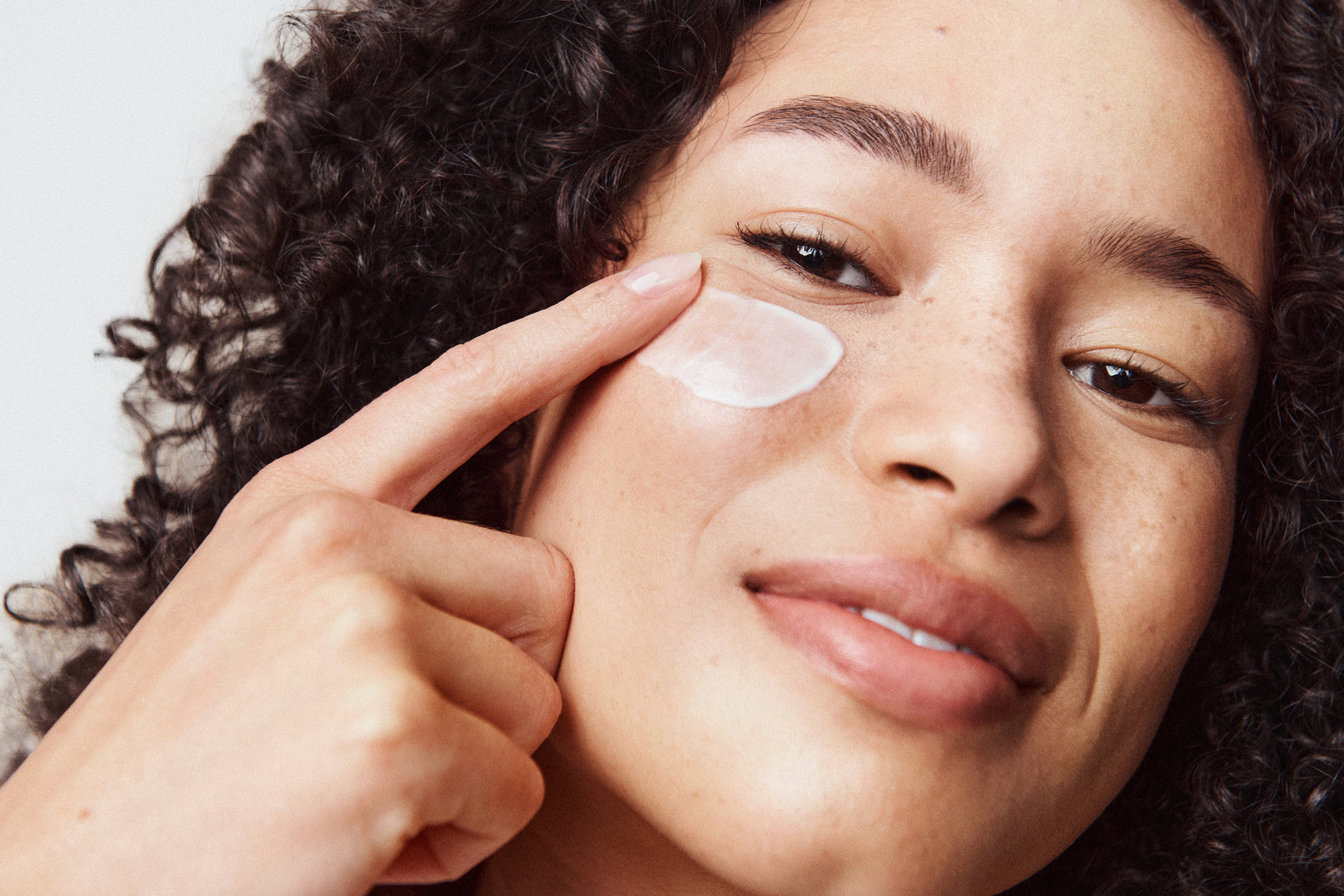 An image of a woman using under eye cream to depuff eyes