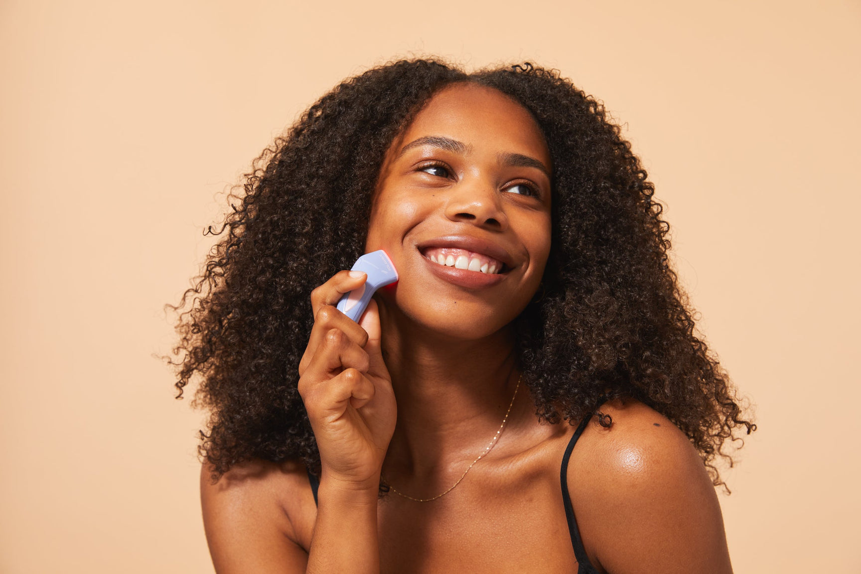 An image of a lady using a blue light therapy device to target pimples
