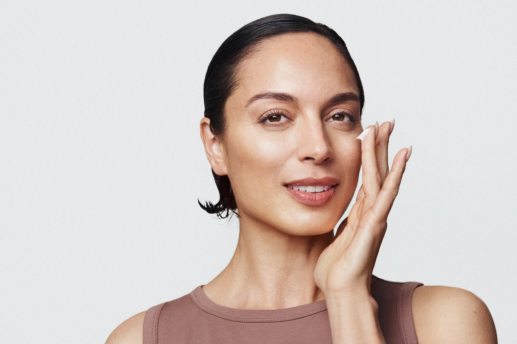 An image of a woman applying Hyaluronic Acid Serum to her face