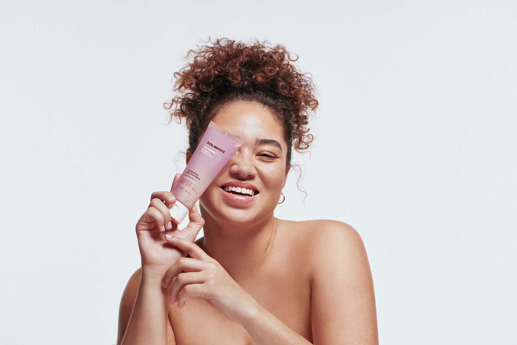 An image of a woman holding up skincare