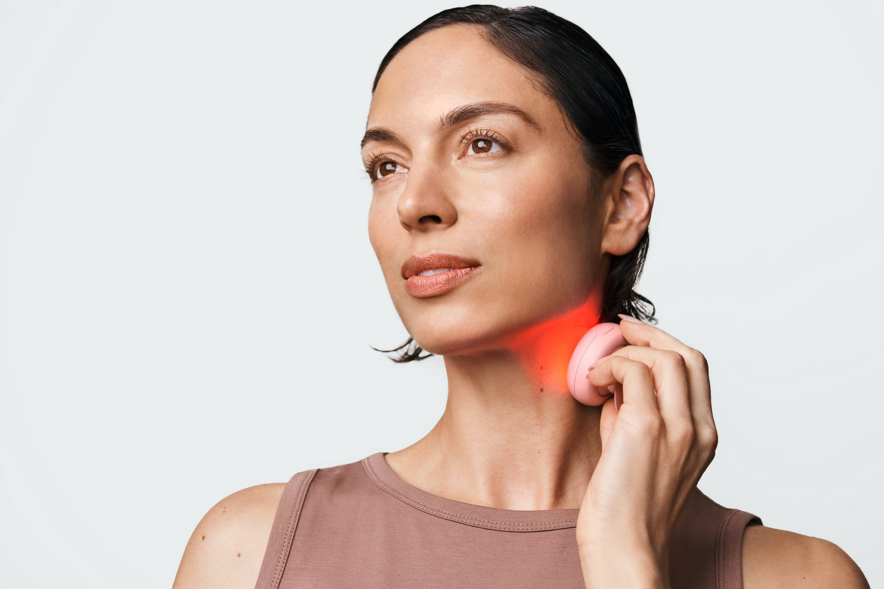 An image of a woman using a red light device on her neck
