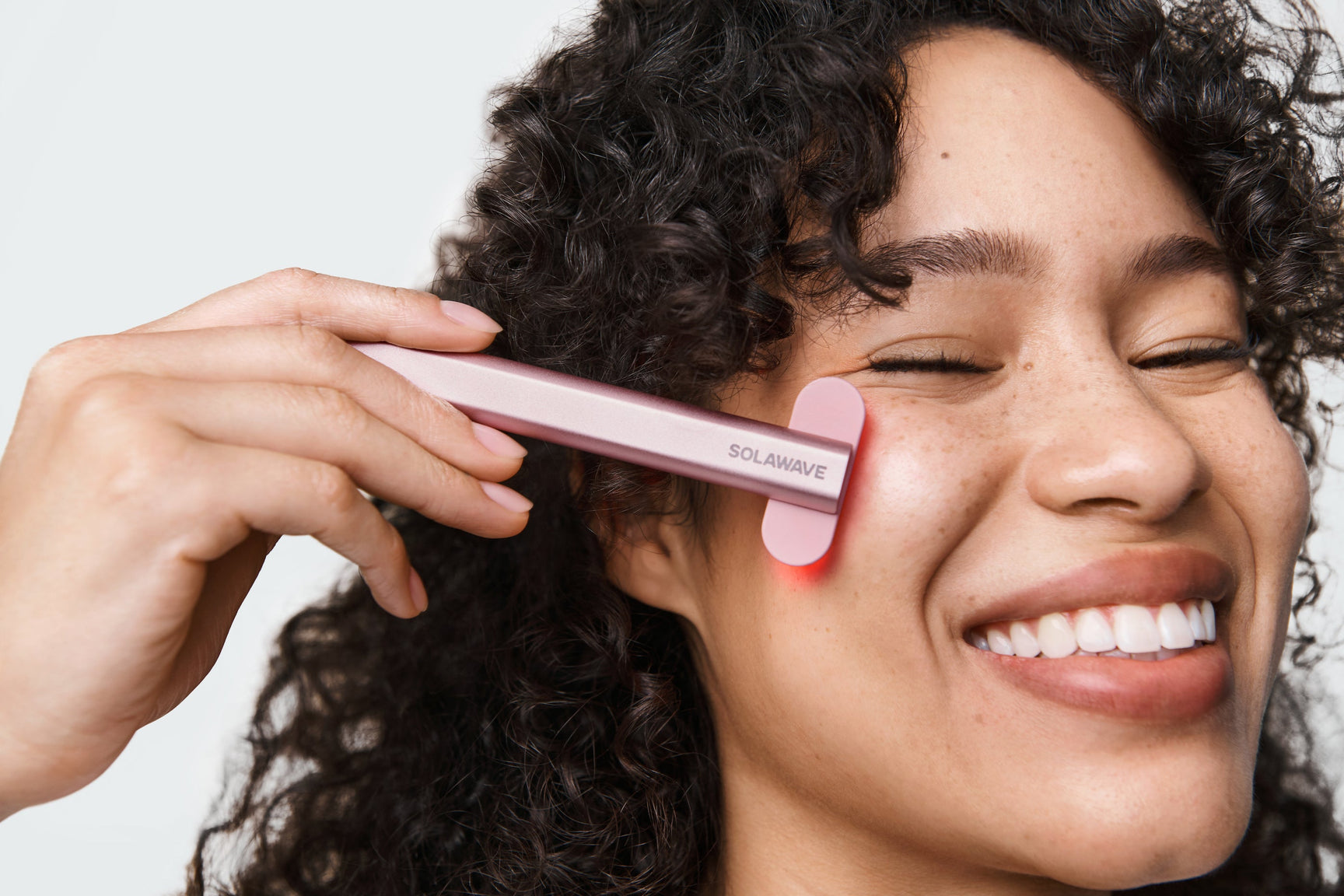 An image of a woman using a red light wand to contour her face