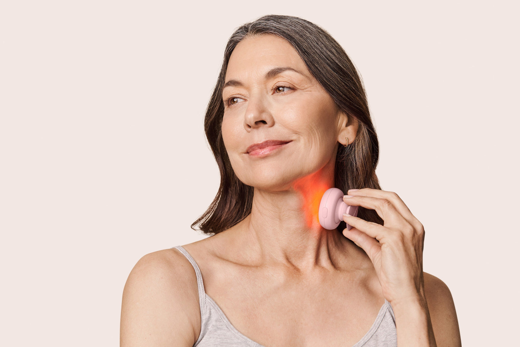 An image of a woman using red light therapy on her neck