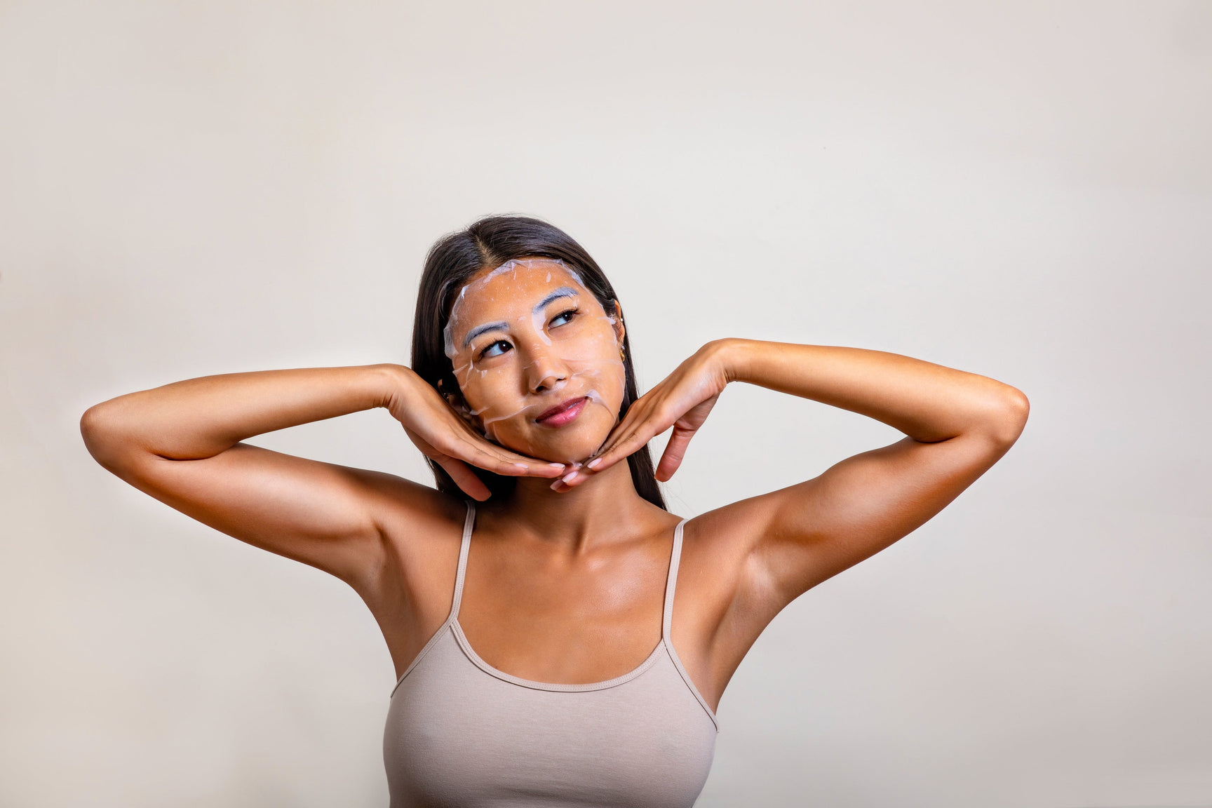 An image of a woman wearing a hydrating sheet face mask