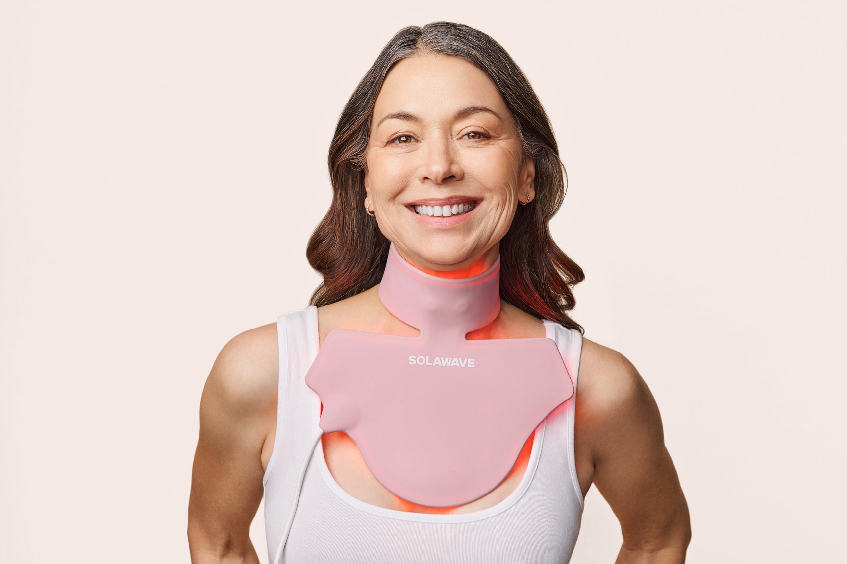 An image of a woman wearing a red light therapy neck and chest mask