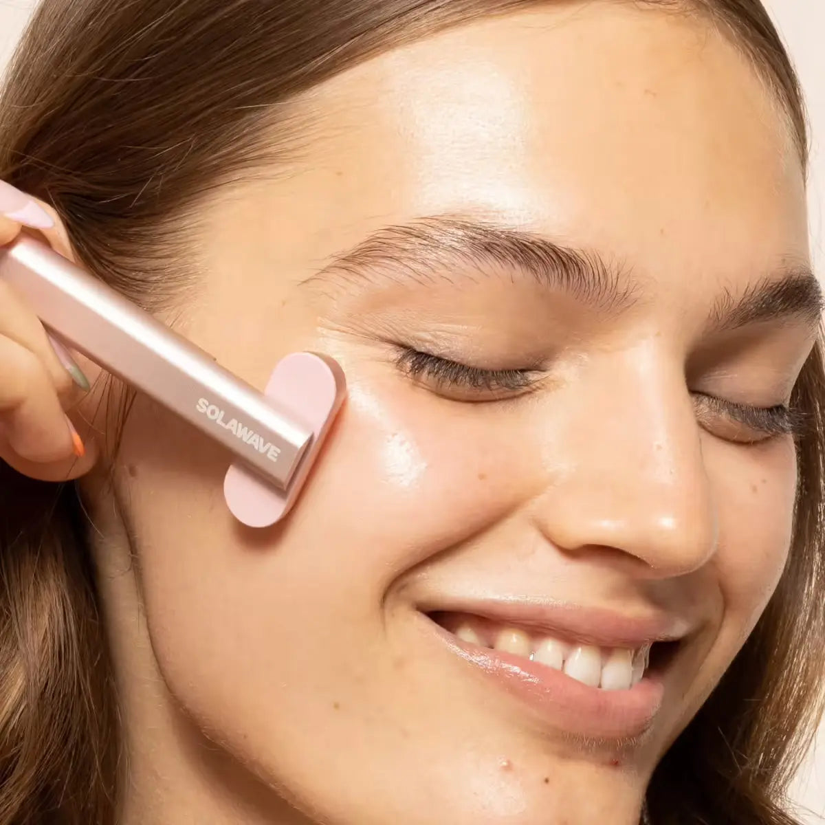 An image of a woman using a red light therapy device on her face