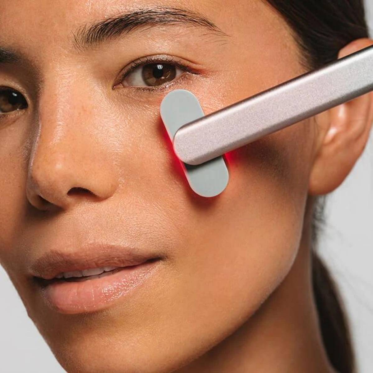 An image of a woman using the Solawave red light therapy wand on her cheeks