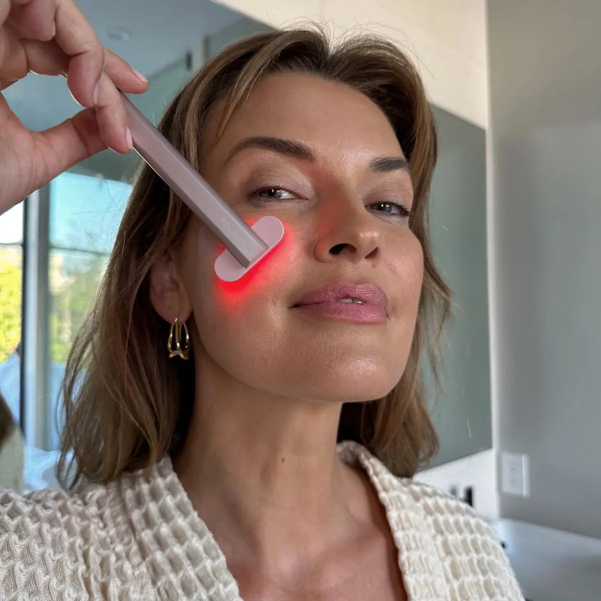 An image of a lady using the Solawave wand red light therapy device on her face