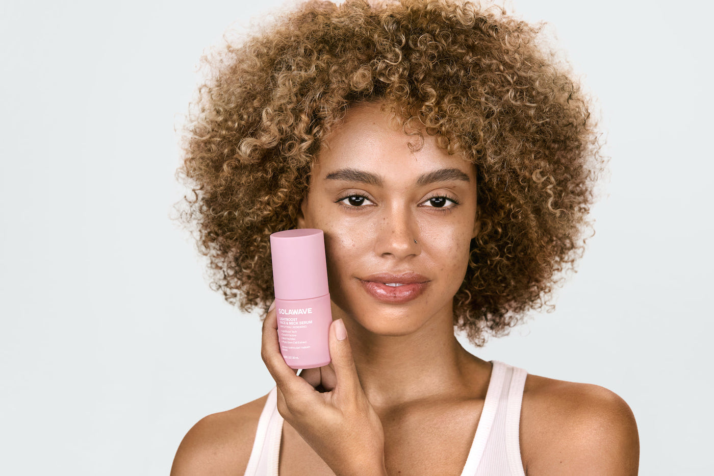 An image of a woman holding up serum setting spray for her face