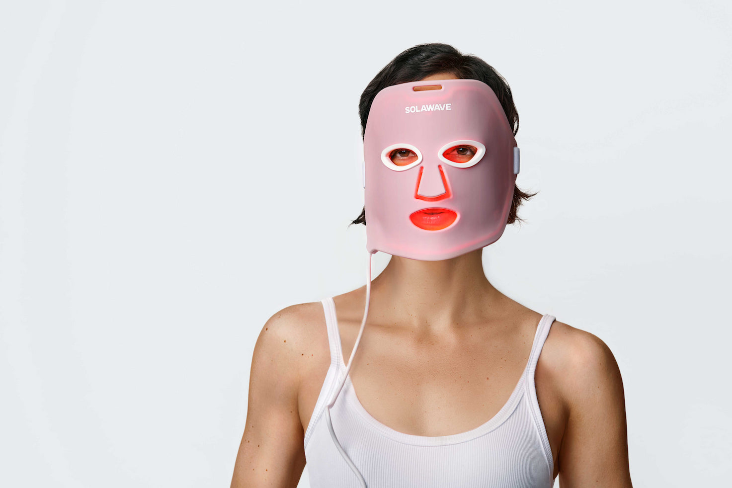 An image of a woman using a red light therapy mask on her face