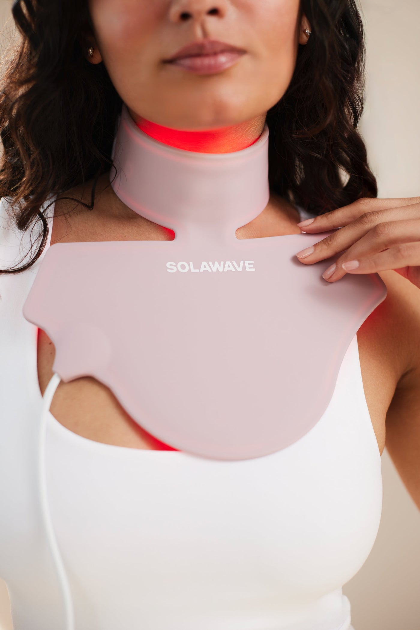 An image of a woman using red light therapy on her neck for her thyroid