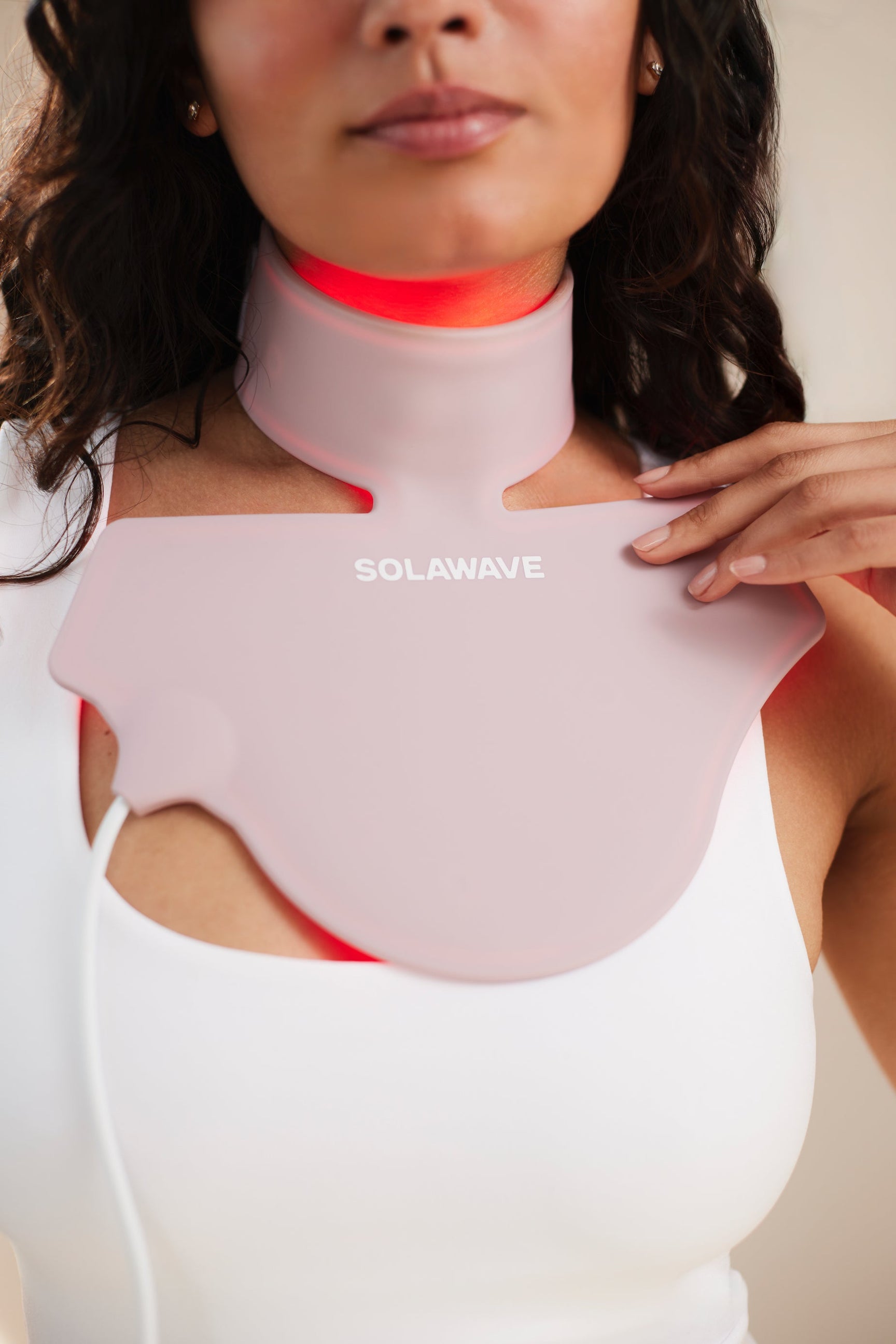 An image of a woman using red light therapy on her neck for her thyroid