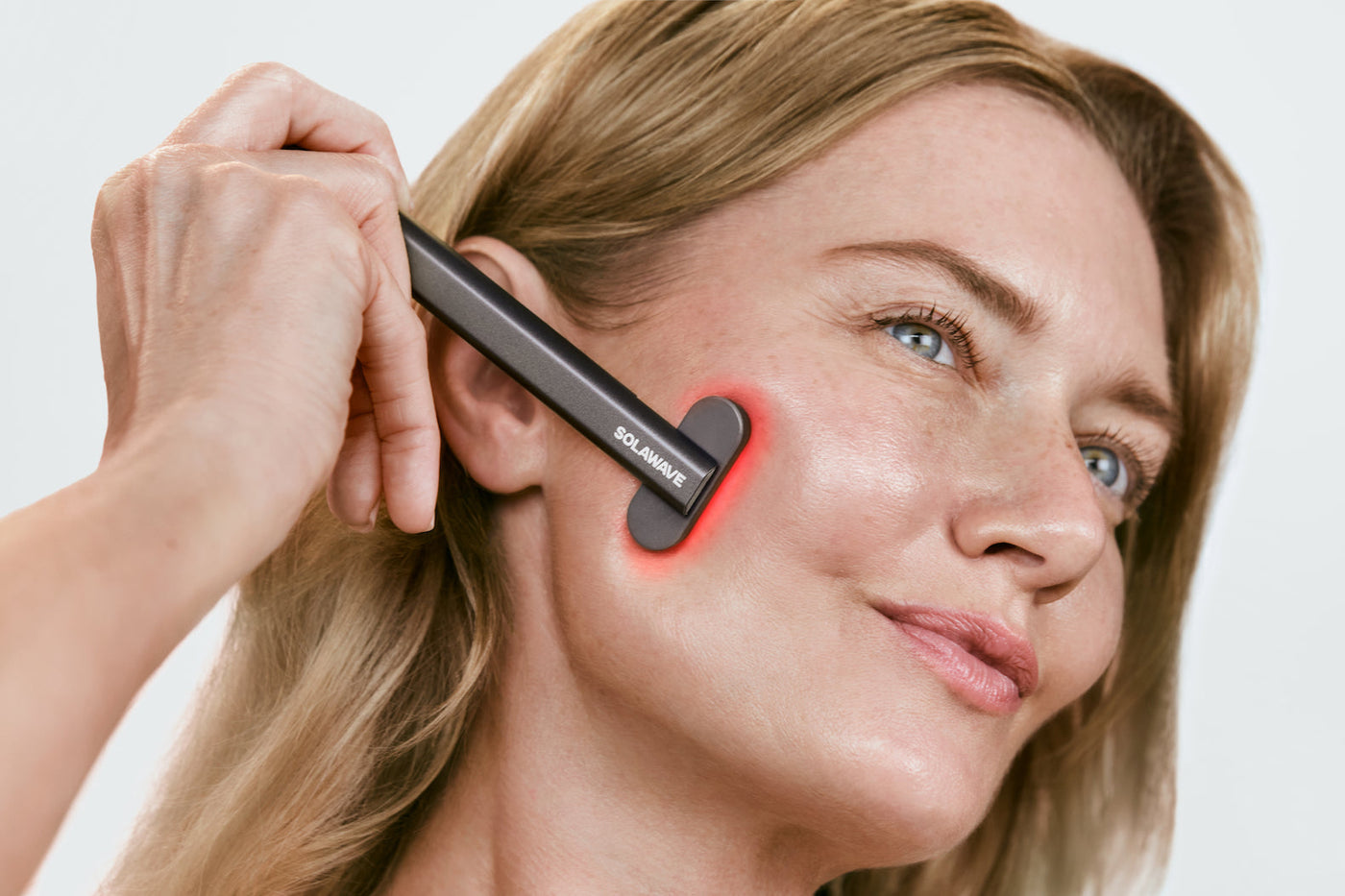 An image of a model using a red light therapy device on her face