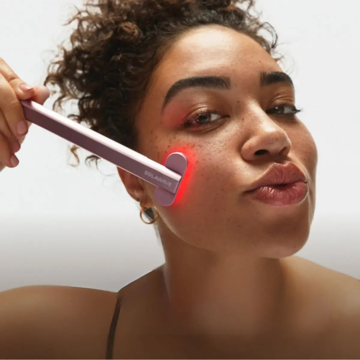 An image of a lady using red light therapy for face blemishes