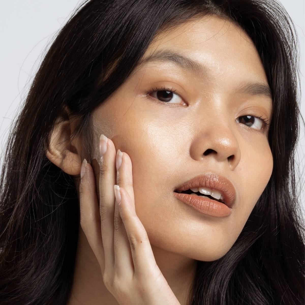 A picture of a model holding her right cheek
