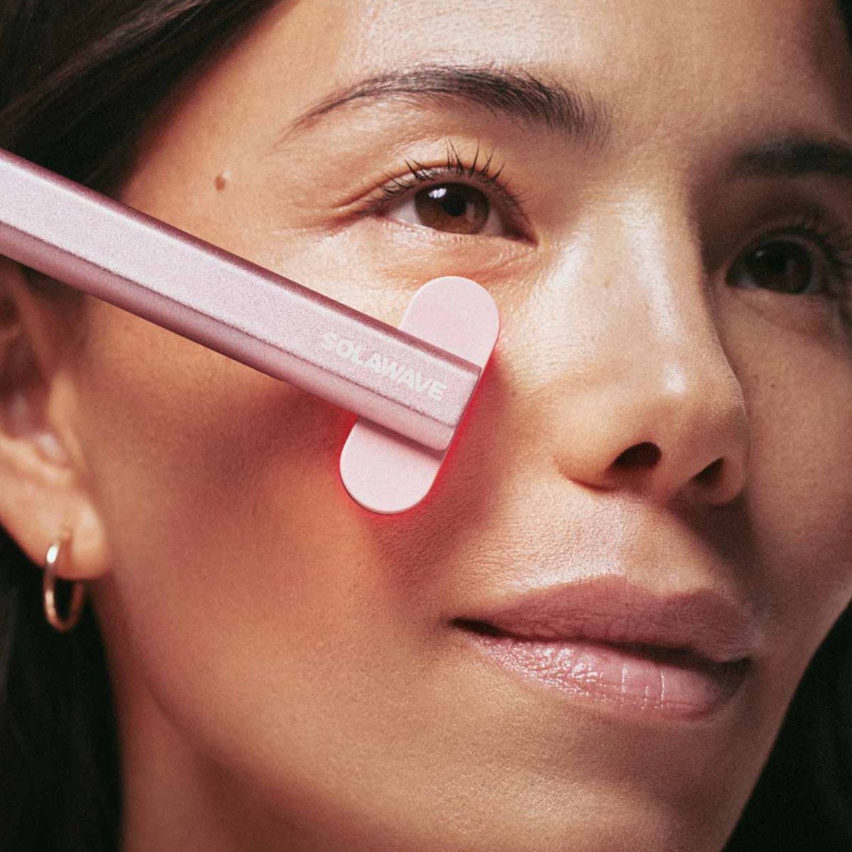 An image of a woman using the Solawave red light therapy wand on her face