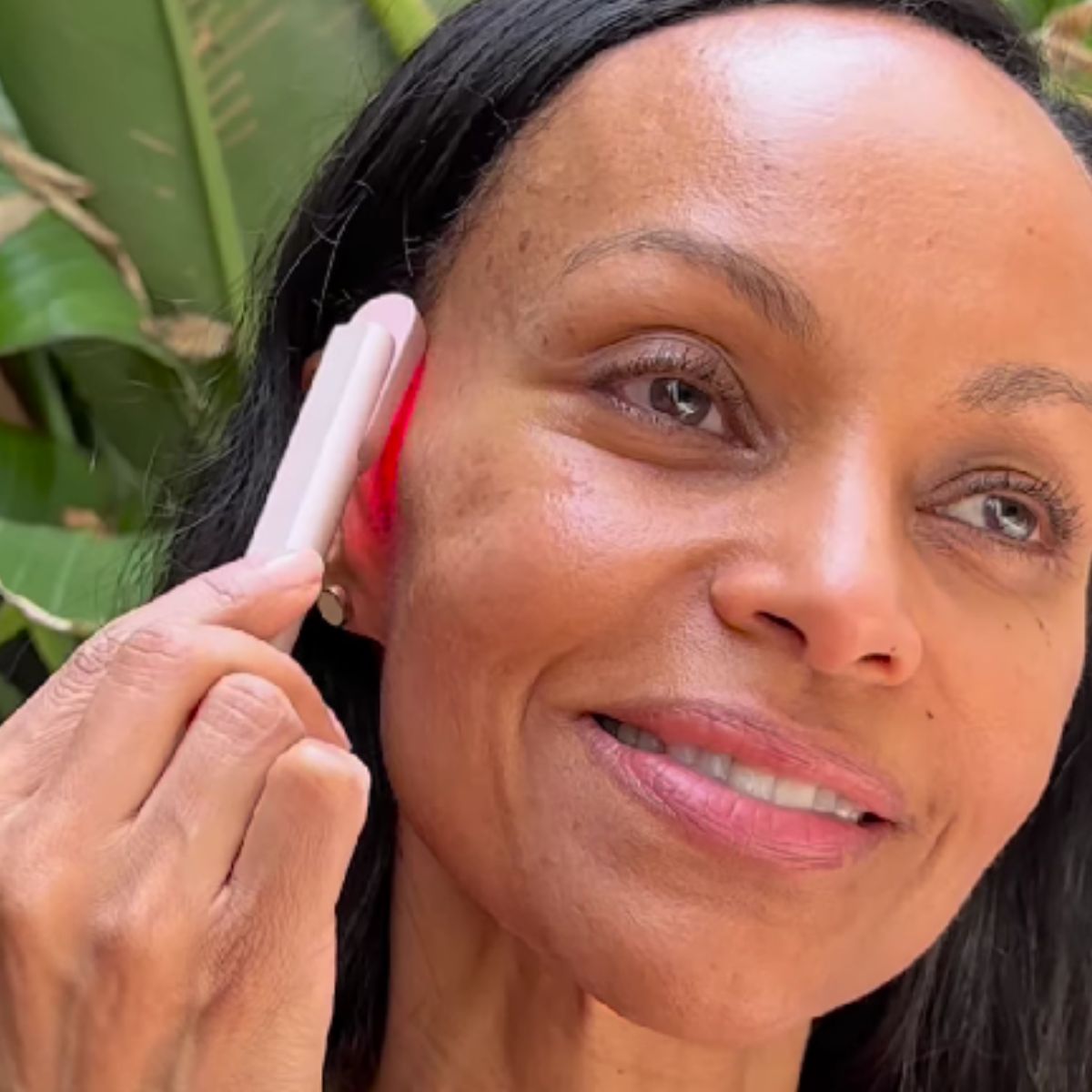 An image of a lady using a red light therapy wand on her cheekbones