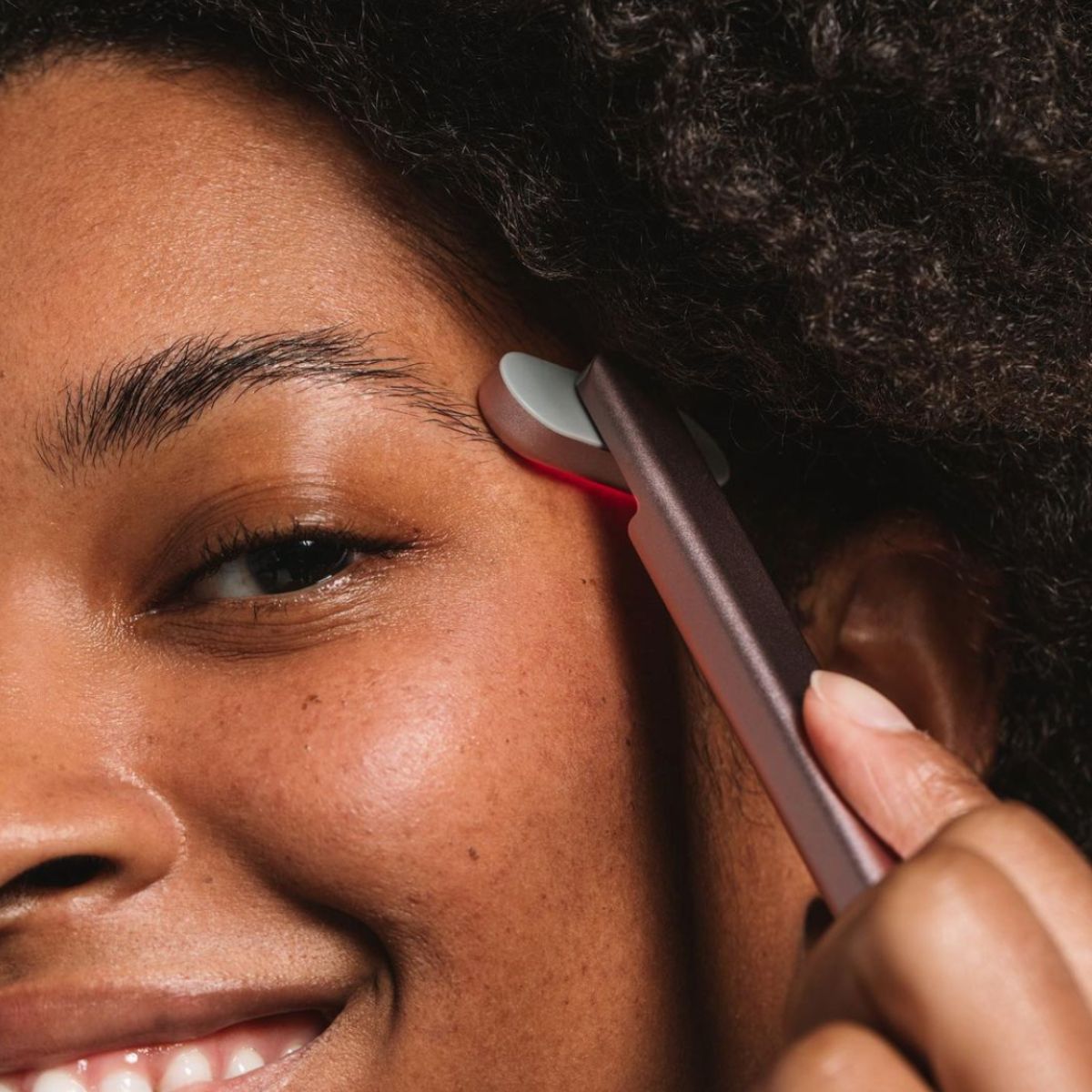 A image of a woman using red light therapy for her face