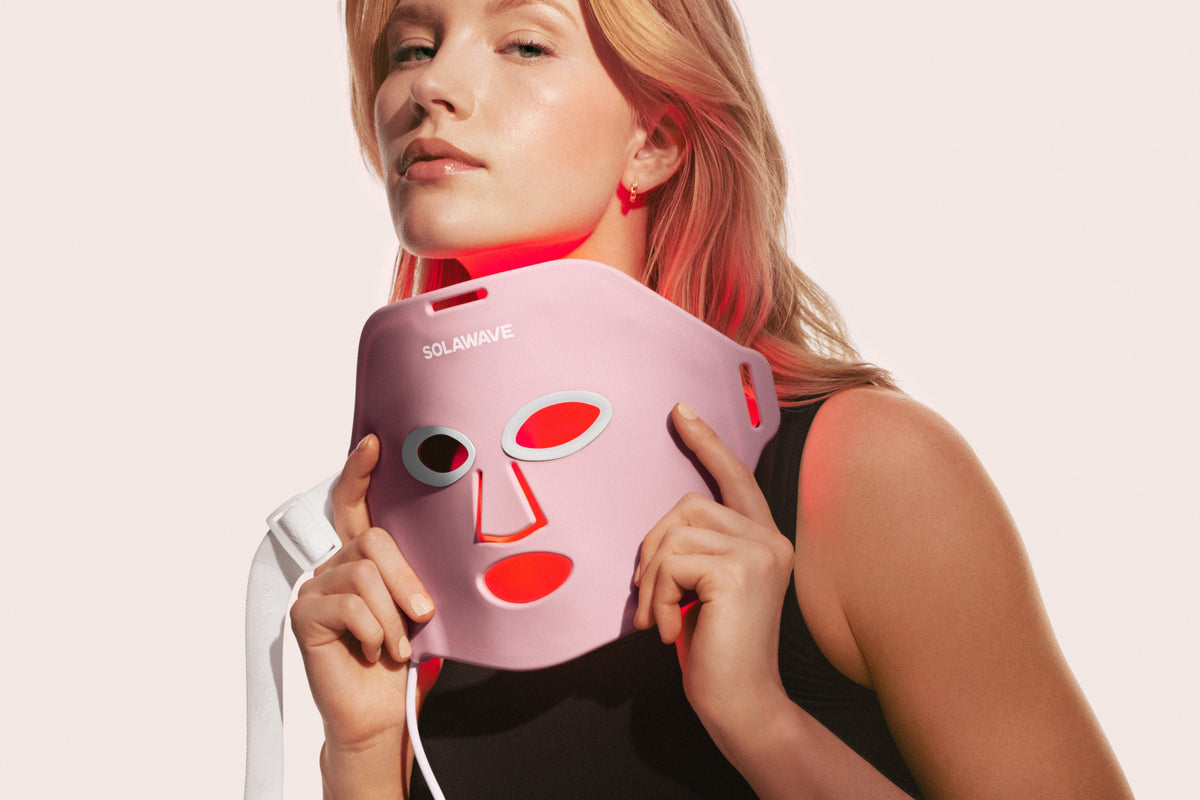 An image of a woman holding up a red light therapy face mask