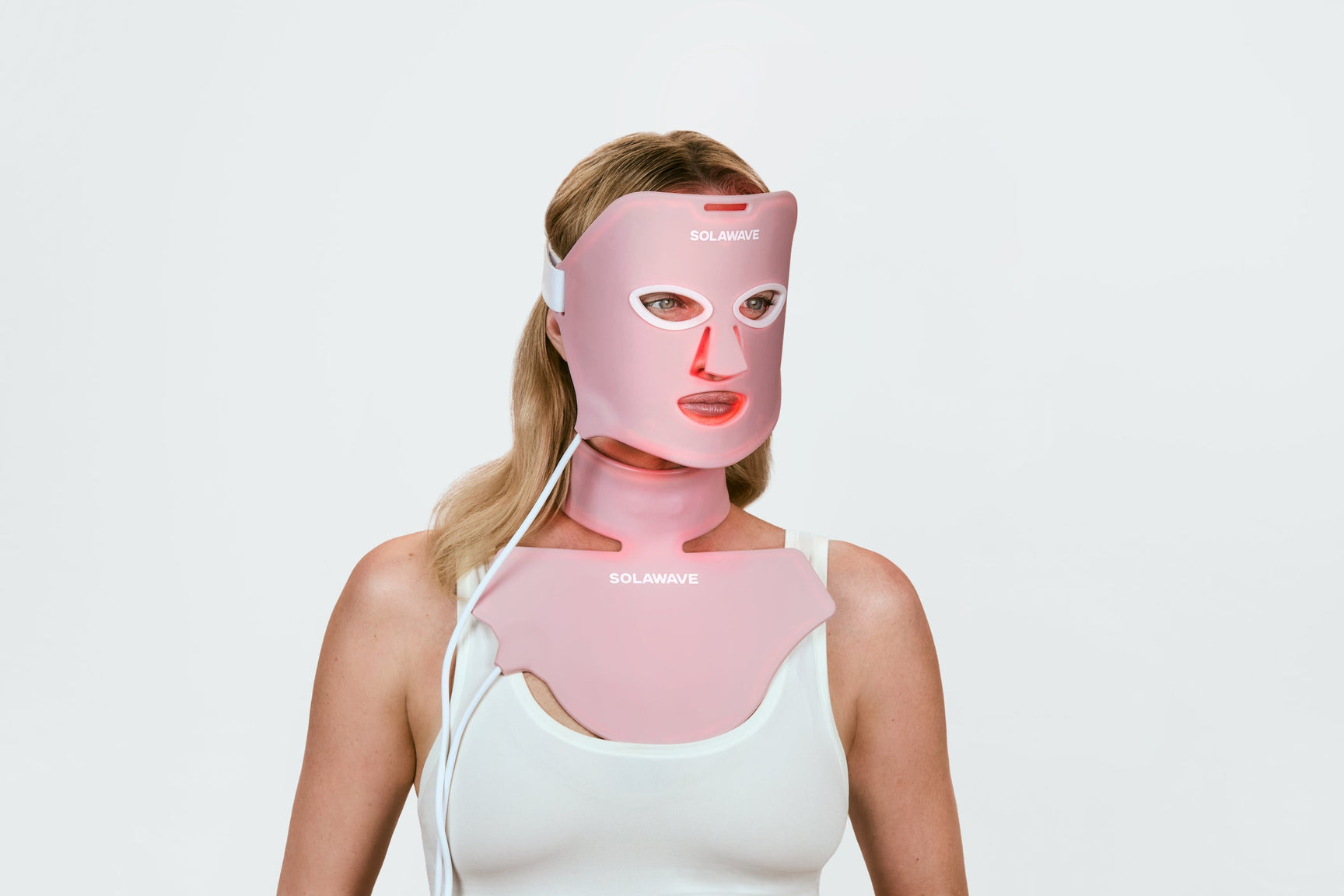 An image of a woman using red light therapy face mask and neck and chest mask