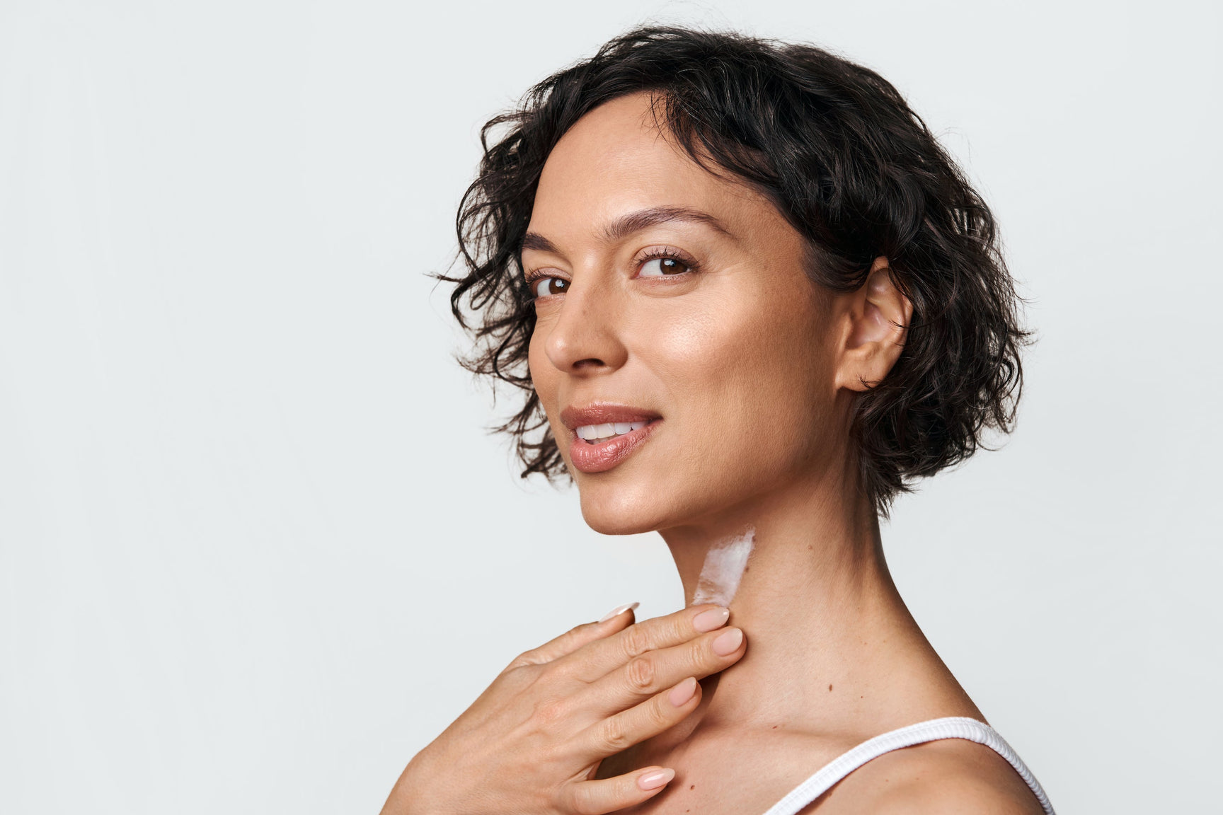 An image of a woman applying serum to her neck area
