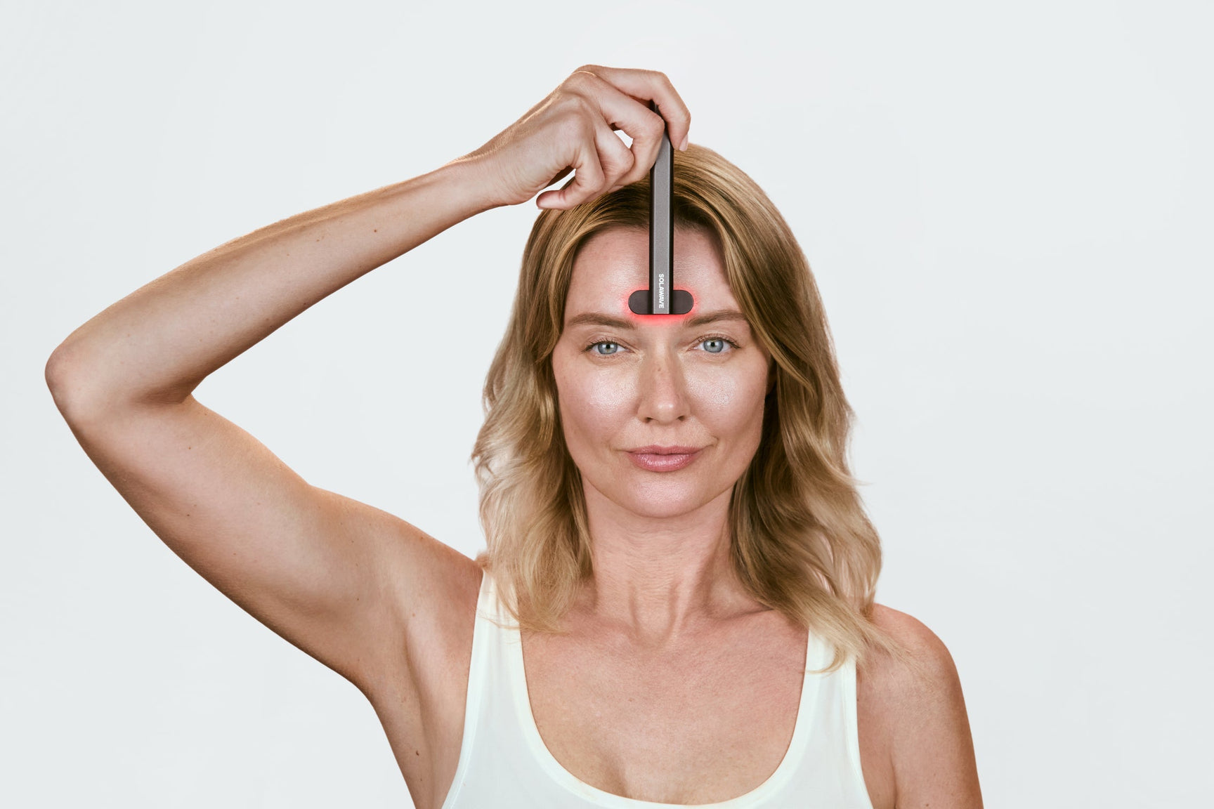 An image of a woman using a red light therapy device on her forehead