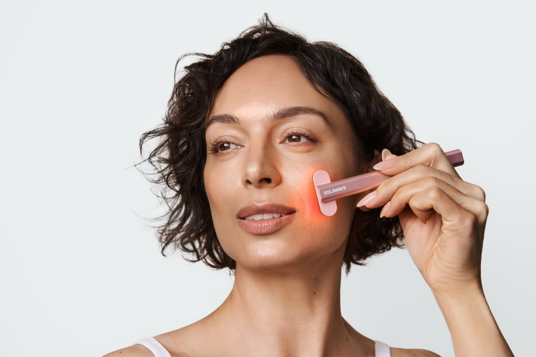 An image of a woman using a red light wand on her face