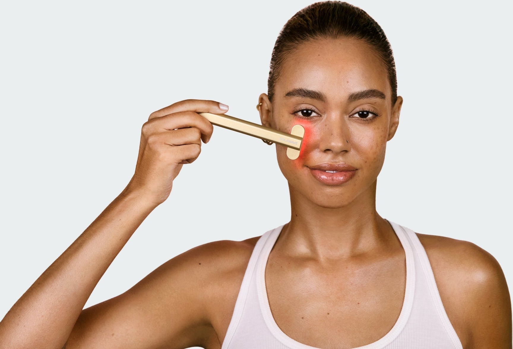 An image of a woman using red light therapy on her face