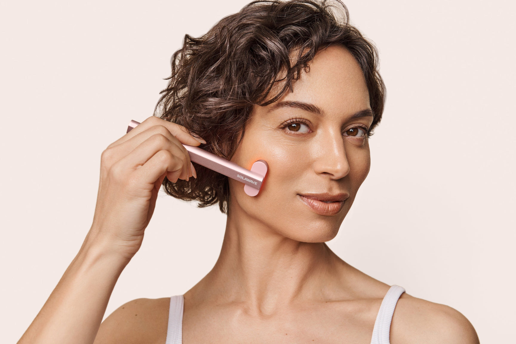 An image of a woman using a red light therapy device on her face to combat wrinkles