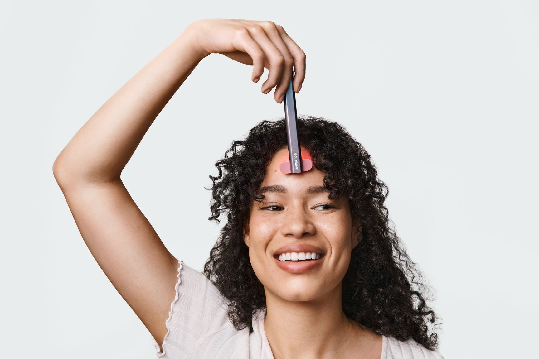 An image of a woman using a red light therapy wand on her face
