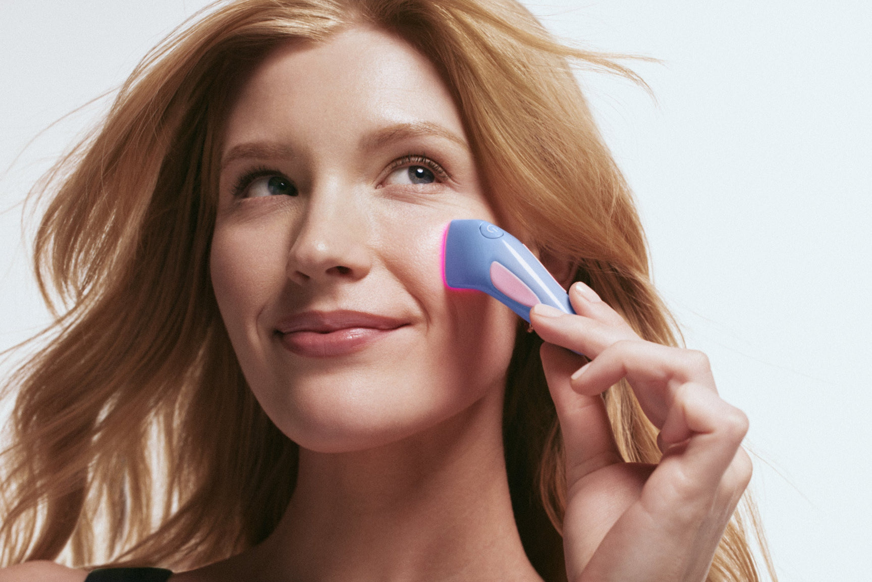 An image of a woman using blue light therapy on her face