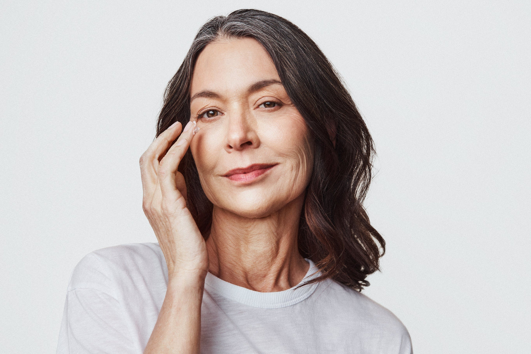 An image of a woman applying cream under her eyes