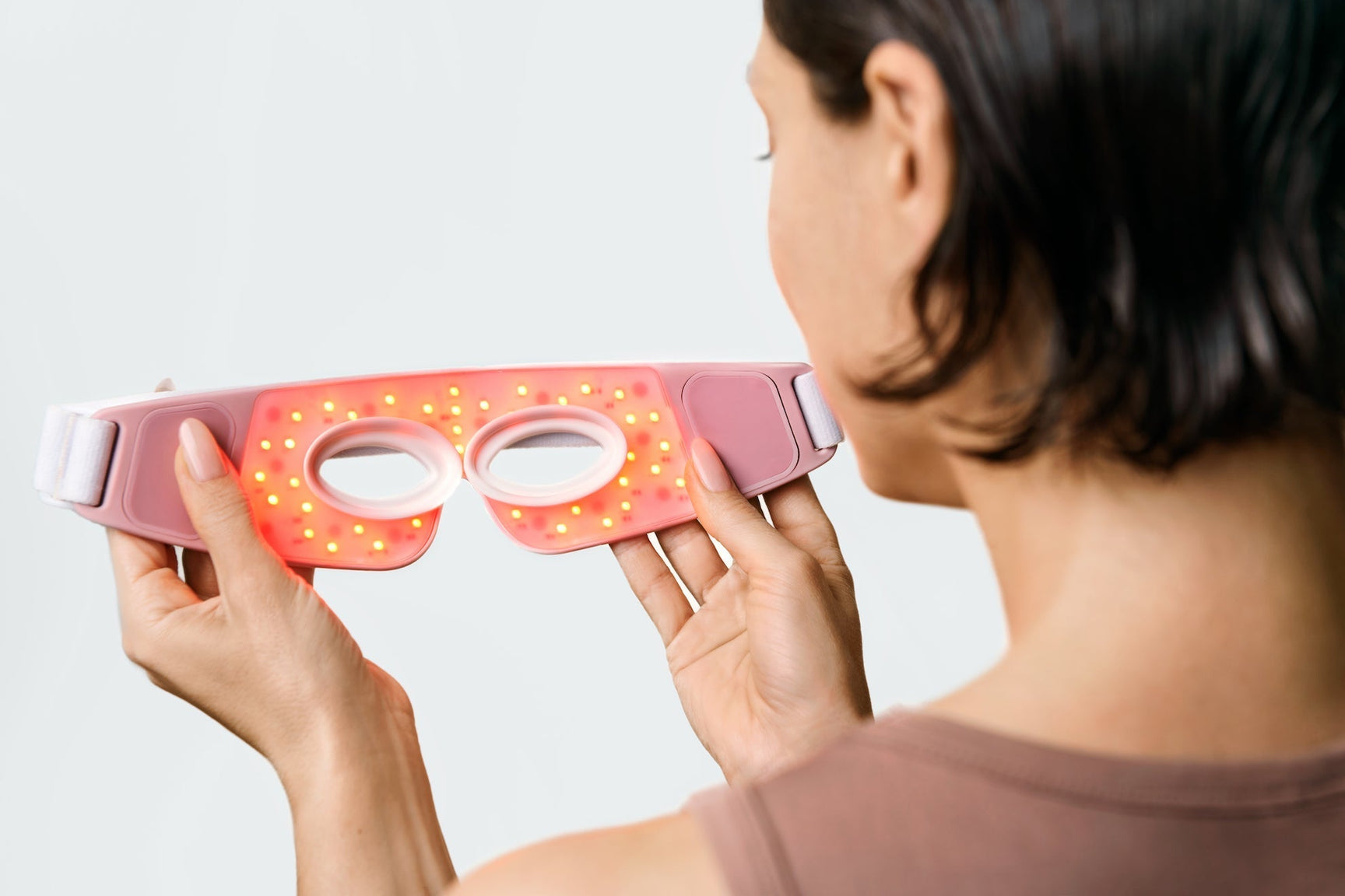 An image of a woman looking at a red light therapy device
