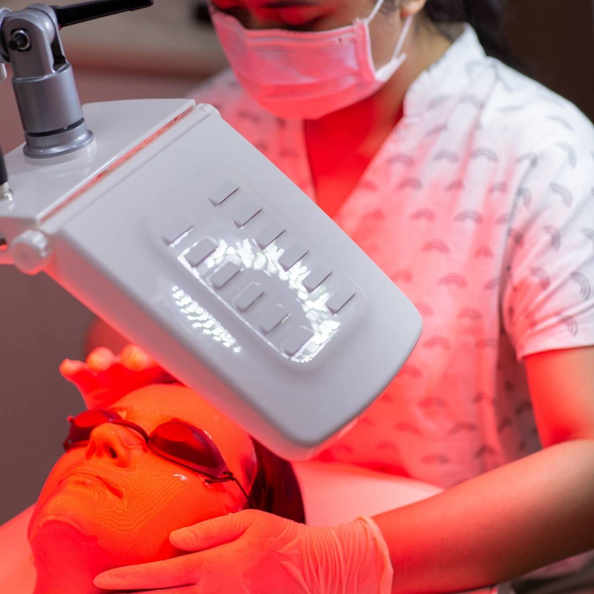 An image of a woman laying down and getting red light therapy treatment on her face 