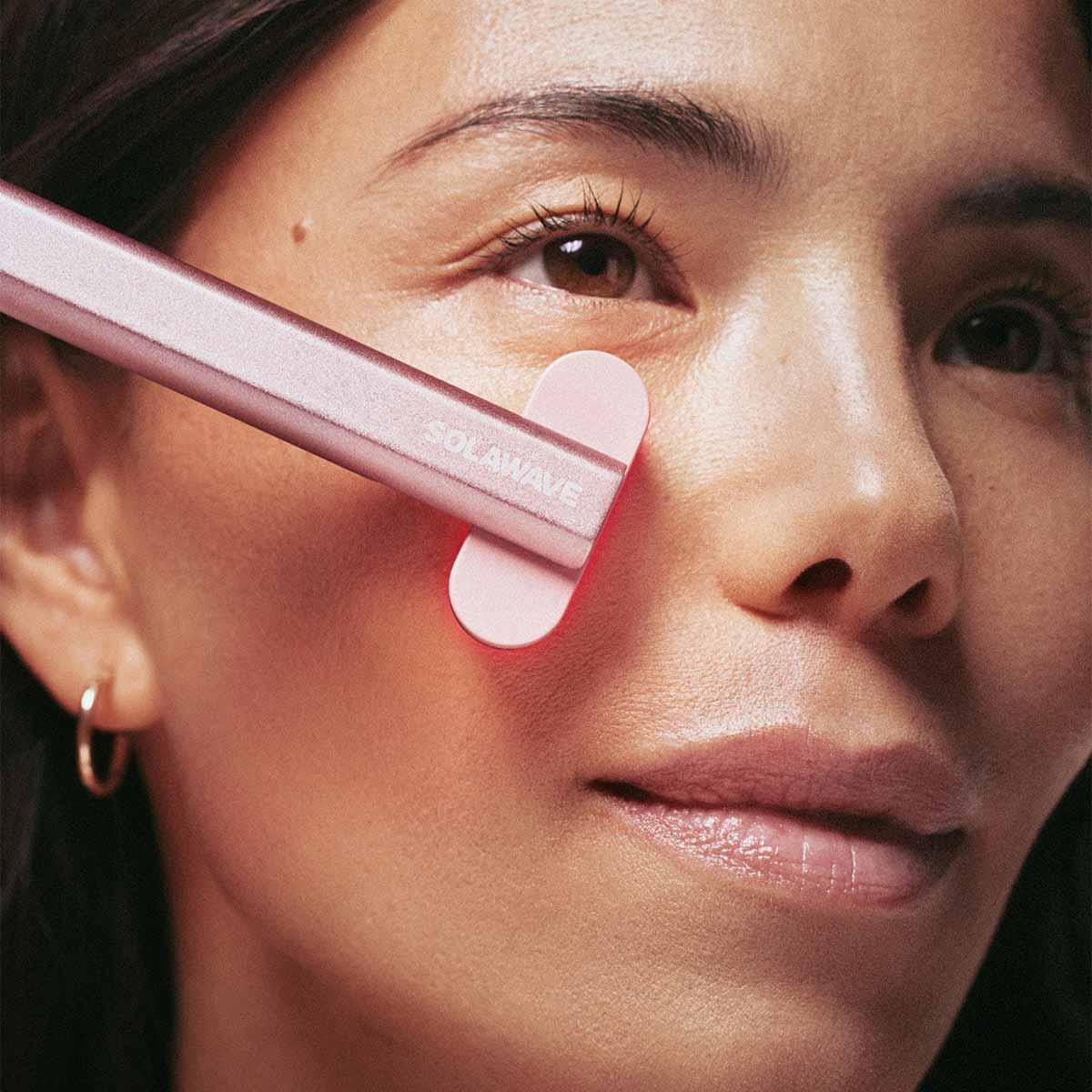 An image of a woman doing red light light therapy on her face