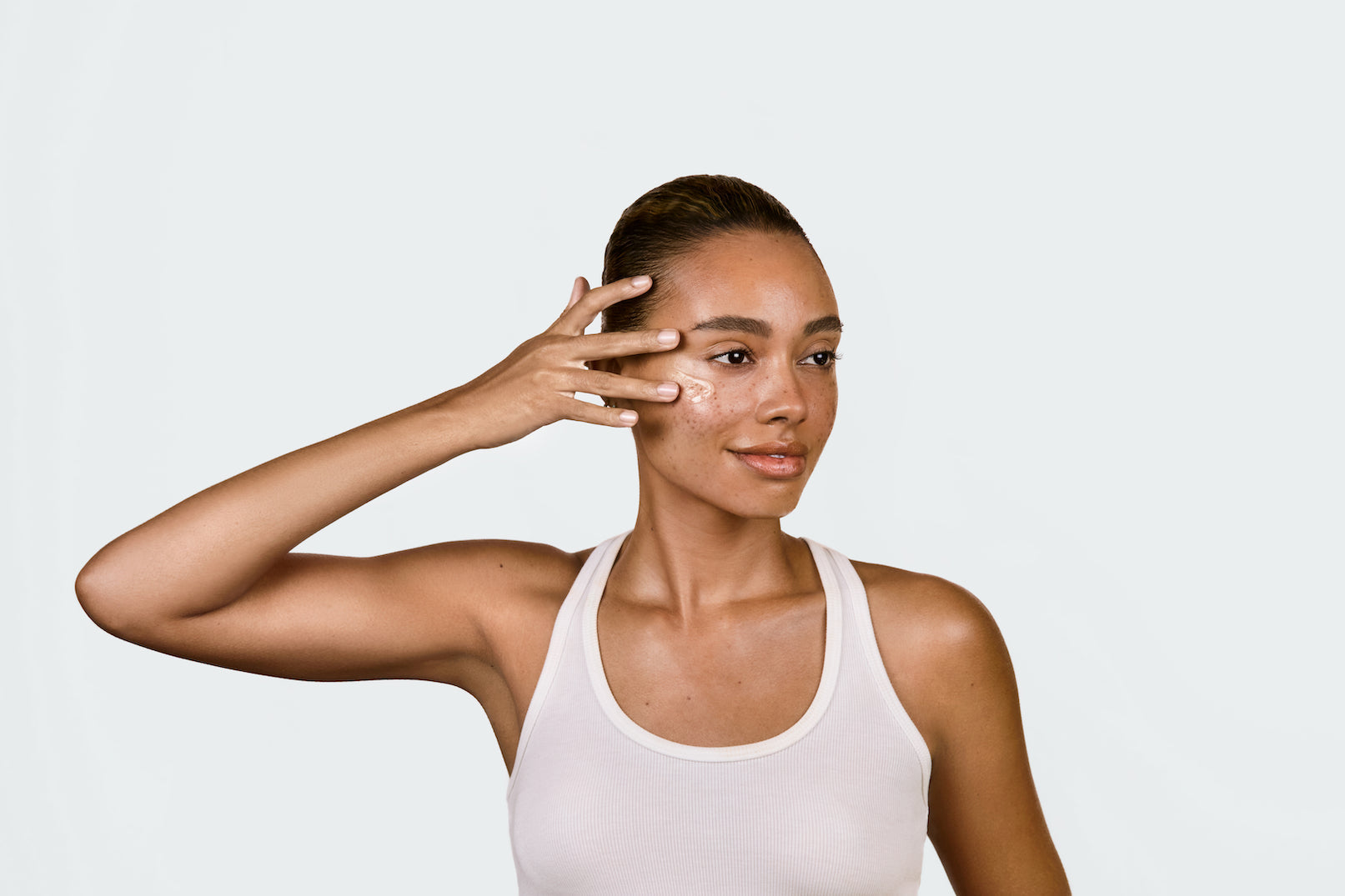 An image of a woman applying serum to her face
