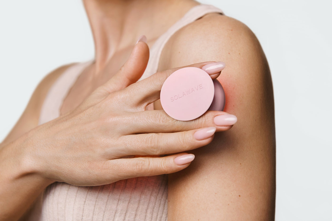 An image of a model using a red light therapy device on her arm