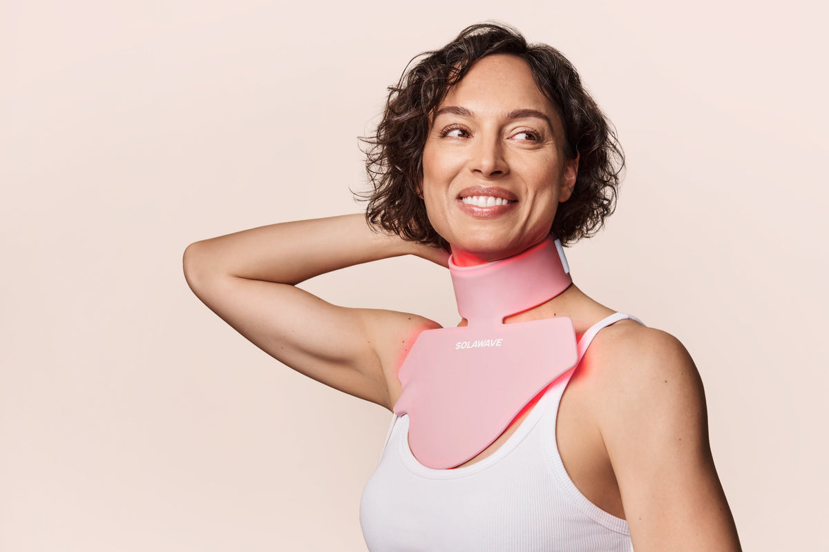 An image of a woman using a red light therapy neck and chest mask
