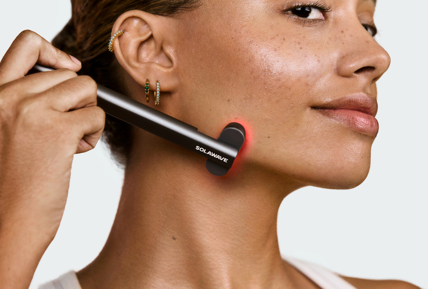 An image of a woman using a red light therapy on her skin
