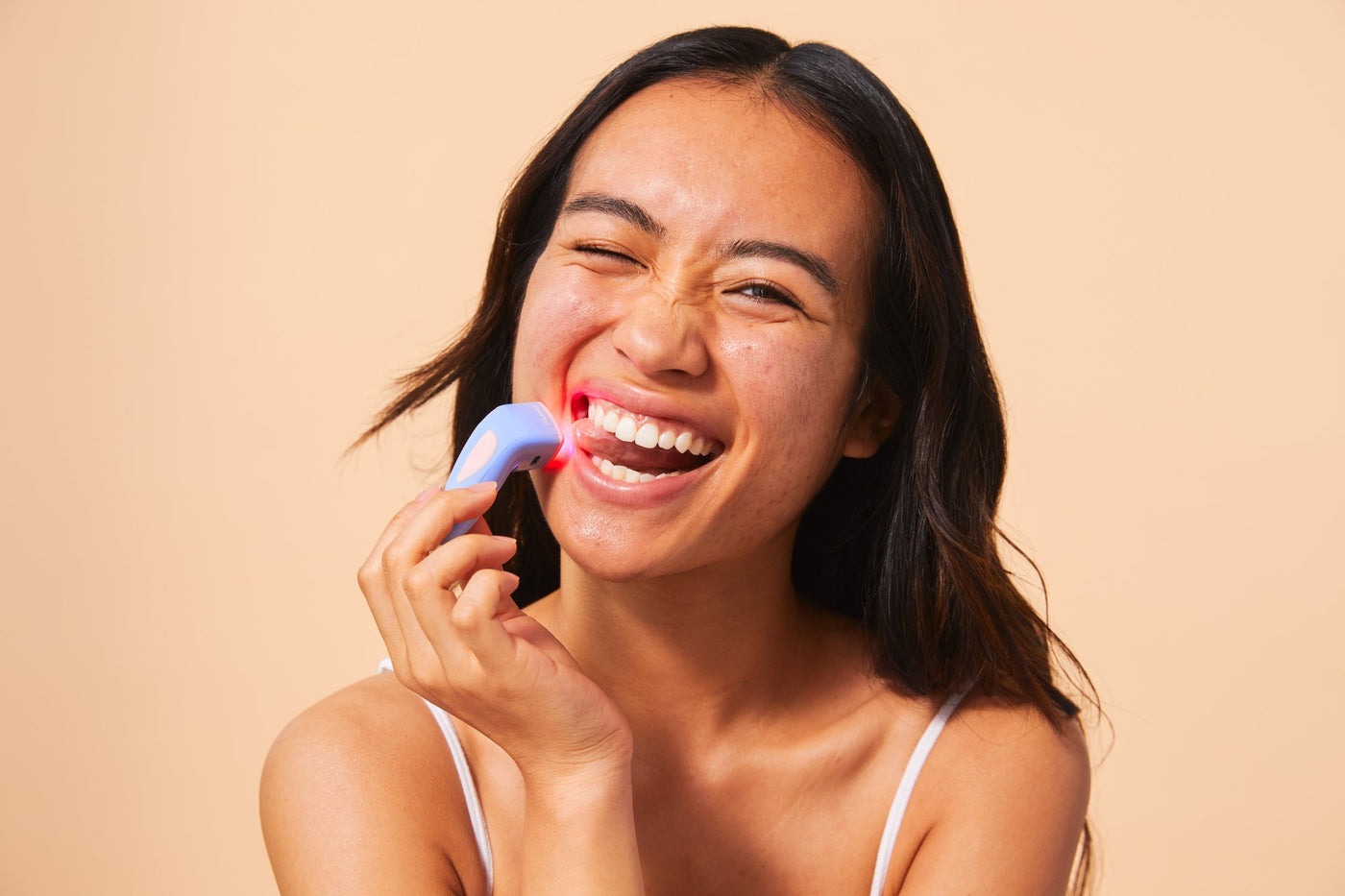 An image of a woman using red light therapy for acne
