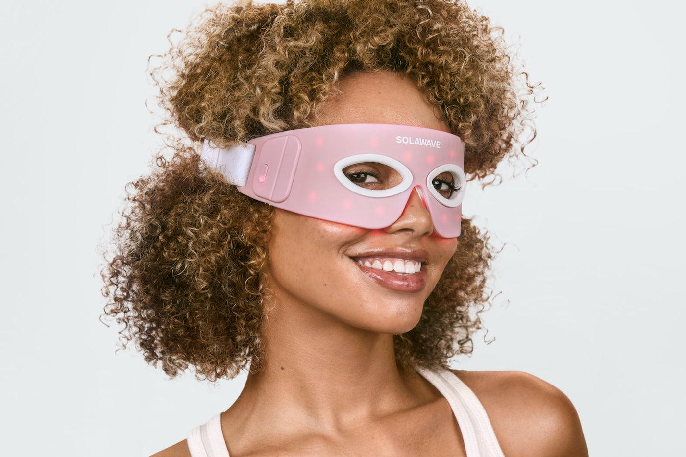 An image of a woman wearing a red light therapy eye mask to target dark circles