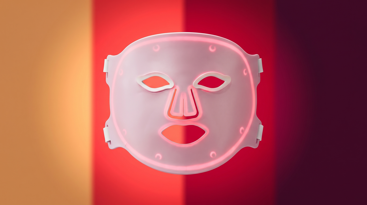 Solawave Wrinkle Retreat Pro LED face mask in front of four bands of coloured light representing its amber, red, deep red and near-infrared wavelengths.