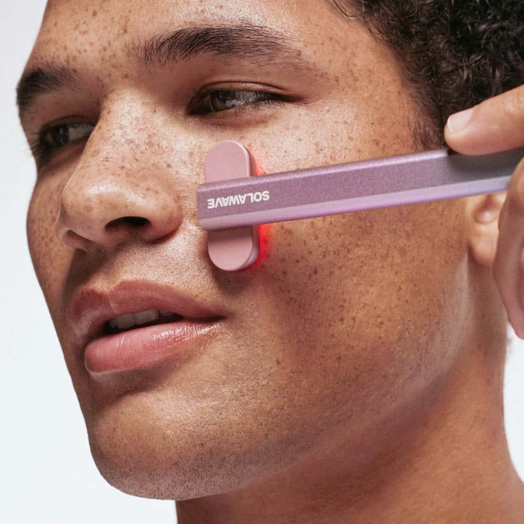 An image of a man using Solawave red light therapy wand on his face