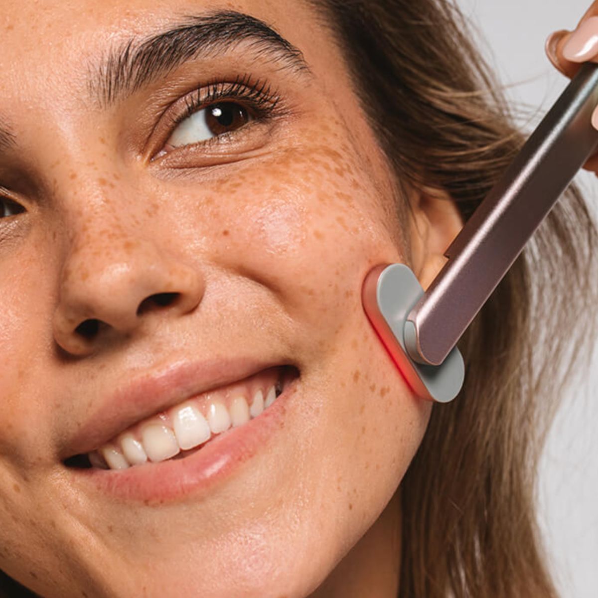 An image of a woman using red light therapy on her face
