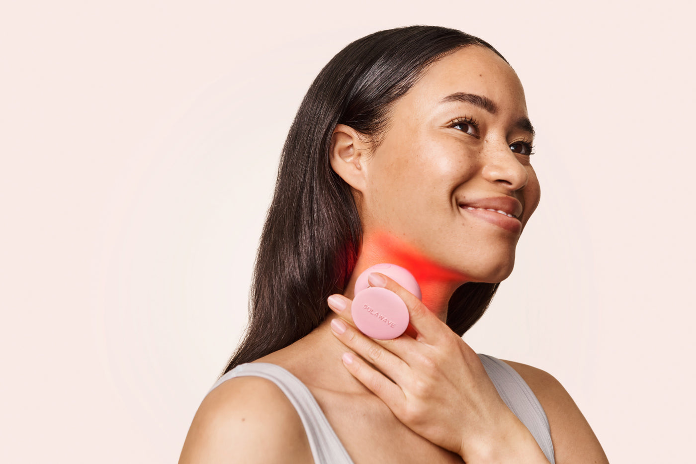An image of a woman using red light therapy on her neck