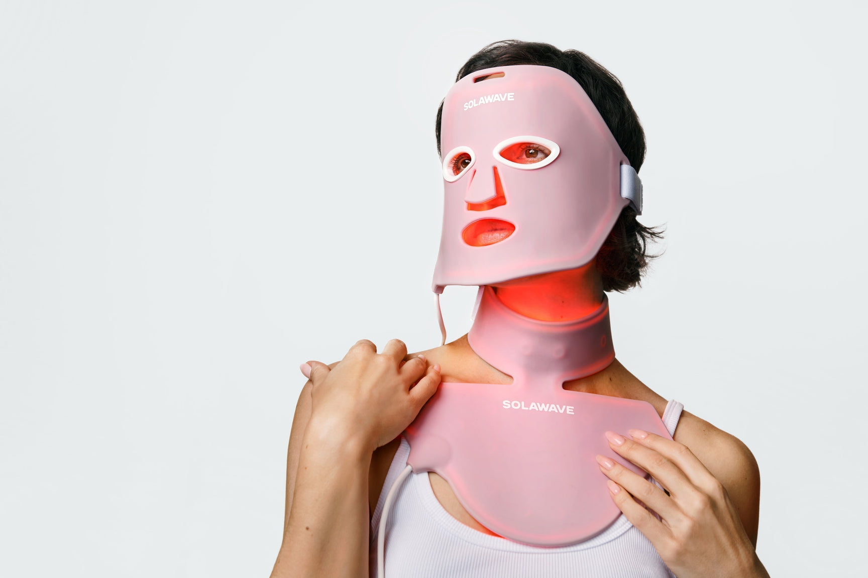 An image of a woman wearing a red light therapy face mask along with a neck and chest mask
