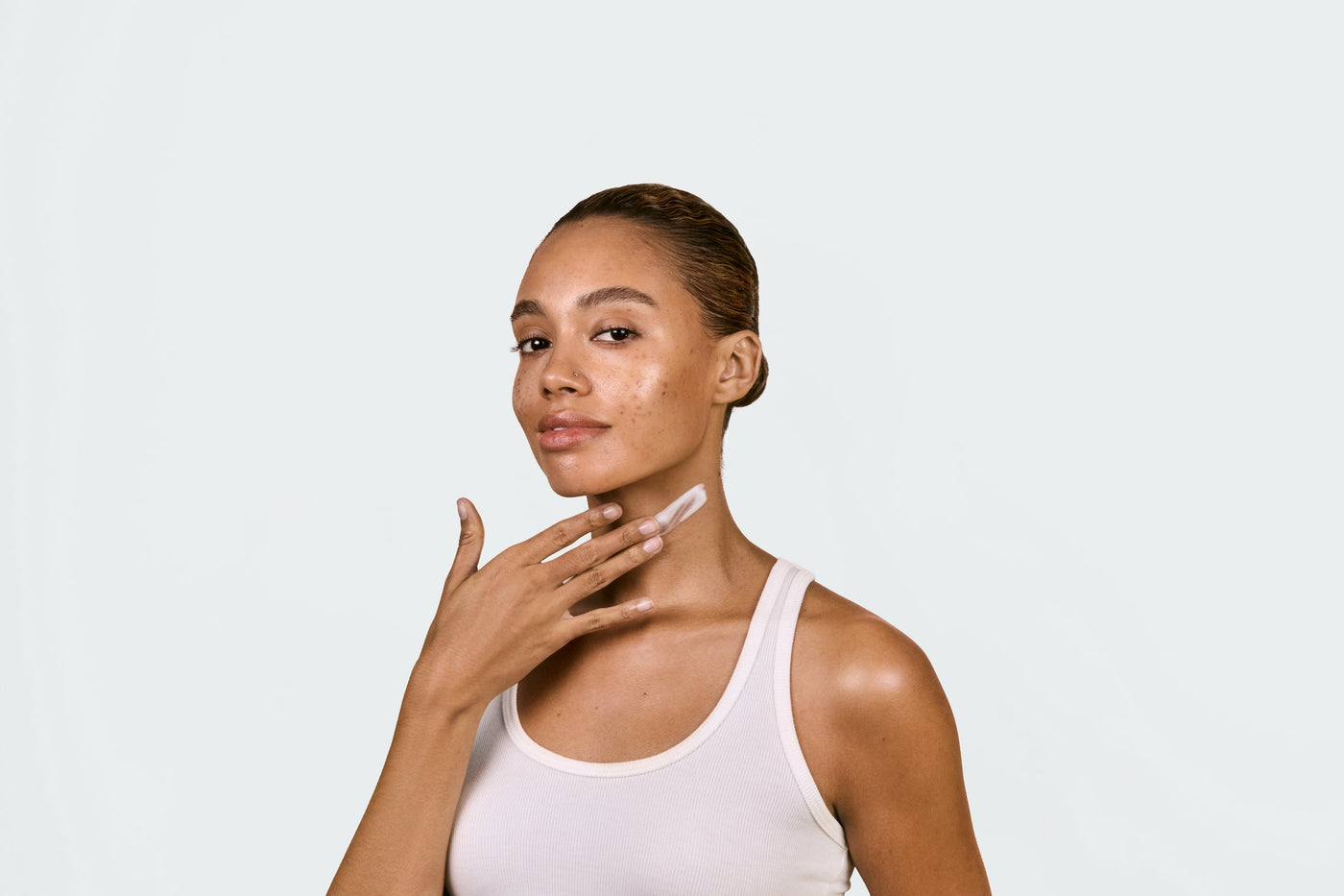 A woman using serum on her neck area before doing red light therapy