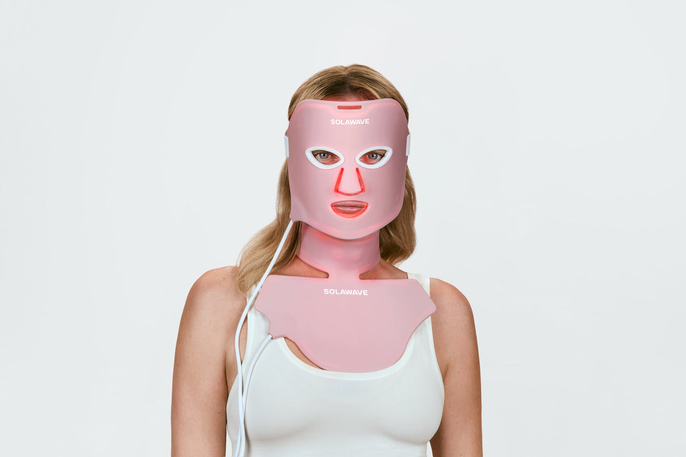 An image of a woman doing red light therapy on her face and neck